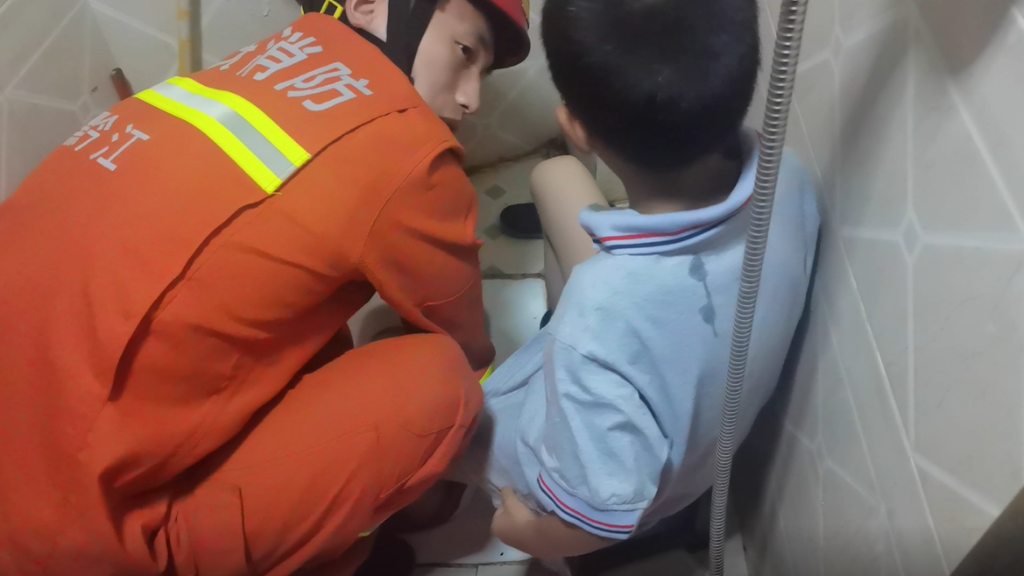 0消防员来回转动小男孩左脚，帮他脱困。黔江消防供图