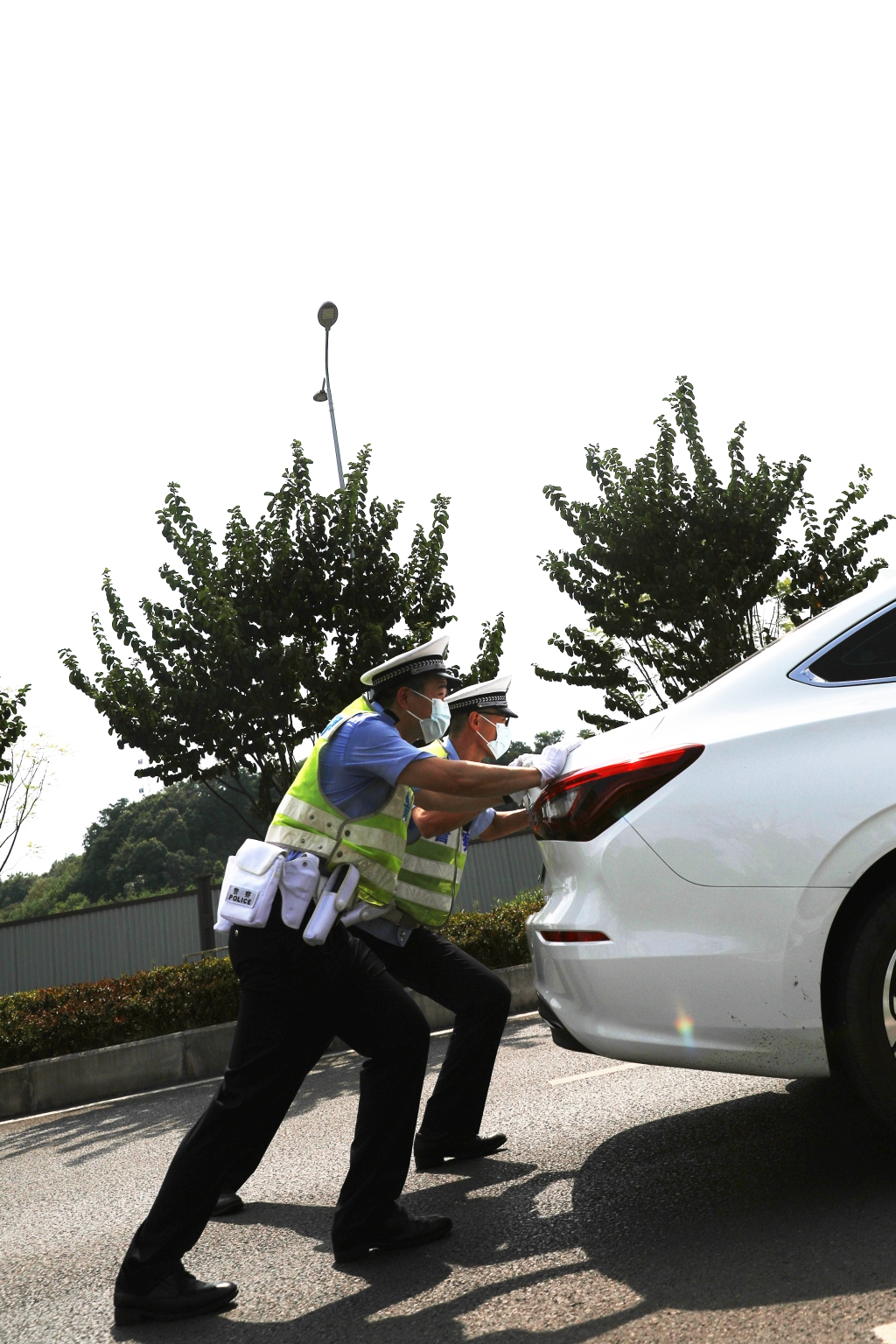 0两名交巡警将抛锚汽车推到路边安全位置，保证道路畅通。重庆市沙坪坝区警方供图