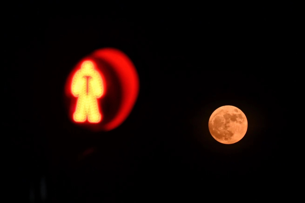 A full moon and a red light complement each other. (Photographed by Li Ye)