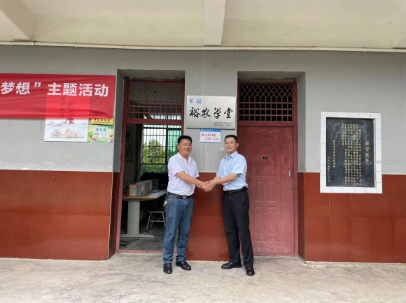綦江区羊角学校校长李启均（左）和中国建设银行重庆綦江支行分管行长周兴旺共同为建行“裕农学堂”揭牌