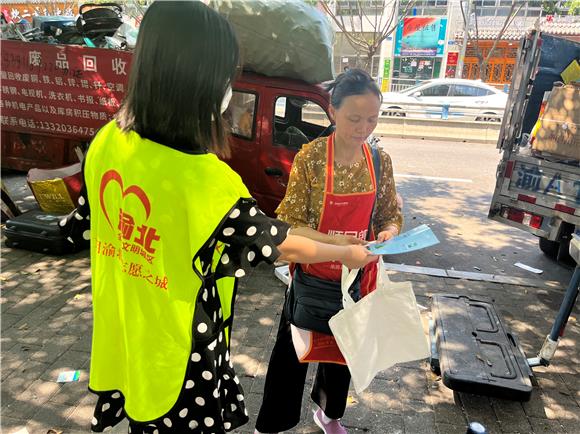 冉家坝社区志愿者向辖区废品回收商户发放环保宣传手册。龙山街道供图