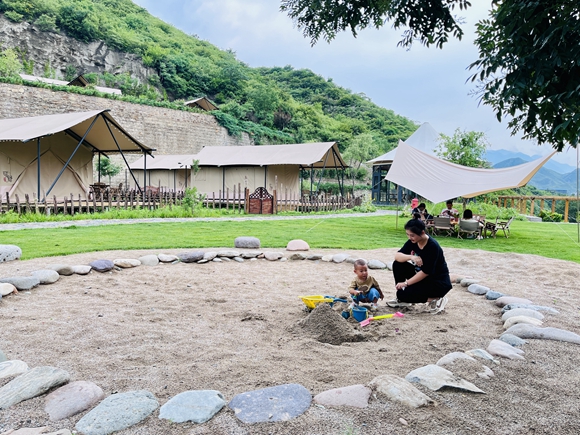 游客带孩子在野三坡景区露营基地的娱乐区玩耍。