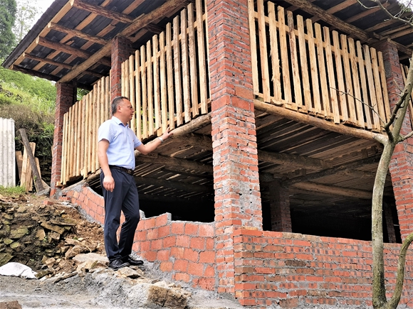 图七：驻村干部查看村民羊舍建设情况。湛江涛，摄