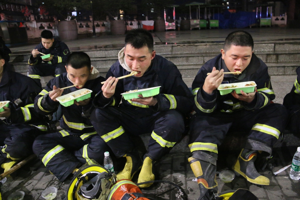 2万惠文（右二）生前与队友在灭火作战间隙吃盒饭。重庆市消防救援总队供图