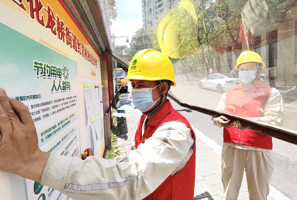 电力工作人员在小区公共区域张贴节约用电宣传海报。国网重庆市区供电公司供图