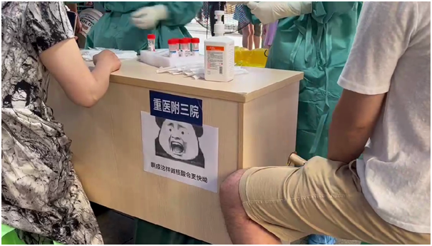 “啊成这样做核酸更快哟！”医务人员在采样台前张贴卡通画，为核酸检测现场增添轻松氛围。