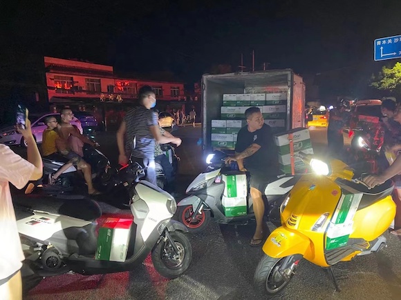 21日晚上，许多摩托车友自发来到现场，帮助运送物资。受访者供图