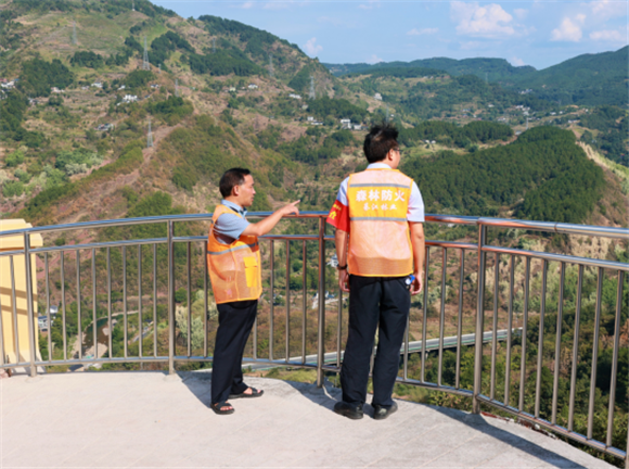 周永君（左一）站在瞭望台上查看远处森林防火情况。通讯员 湛江涛 摄