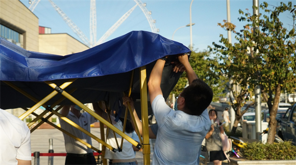 来自华侨城集团的志愿者协助街道工作人员搭建帐篷。礼嘉街道供图 华龙网发