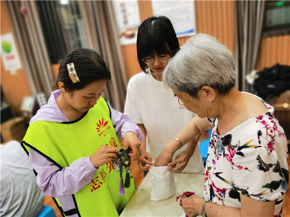 睦邻路社区志愿者帮助老奶奶制作香囊。仙桃街道办事处供图  华龙网发