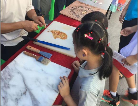 1小朋友正在观摩糖人艺术。白市驿镇供图