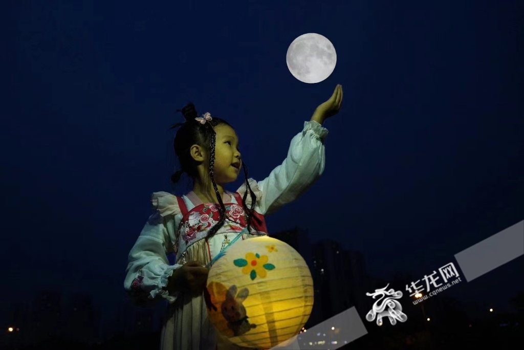 On 10th September, a little girl “holds” the full moon and play with it at the University Town of Shapingba District.