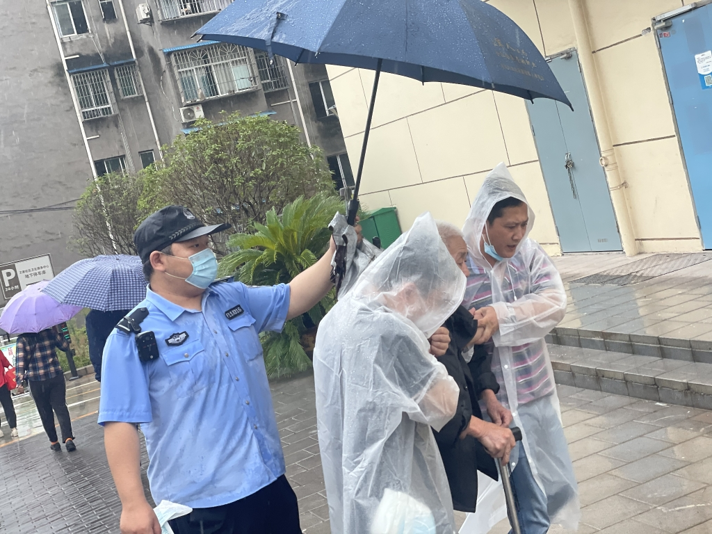 Yu Zhonghua, an auxiliary police officer from Wangjia Police Station, was holding an umbrella for the injured elderly. (Photo provided by the police station in Yubei District)