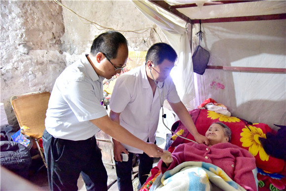 陈治宇同医生一道给卧床的老人检查身体。通讯员 郑红均 摄