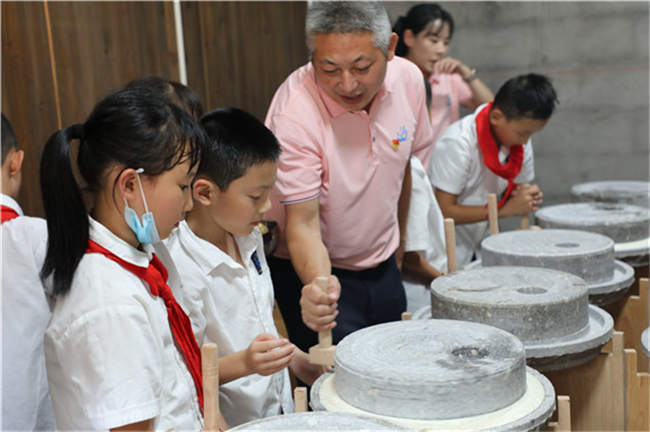 巫溪县城厢小学校长给学生示范如何使用石磨。城厢小学供图 华龙网发