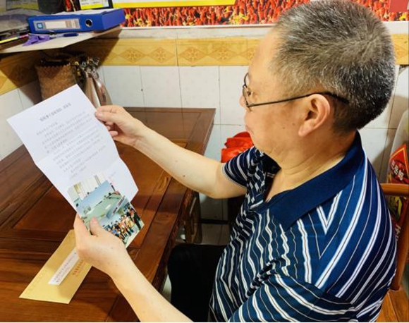 在广东广州，一名税务家属正在仔细查看“税务家书”和孩子的工作照、生活照。 通讯员 唐宇 摄