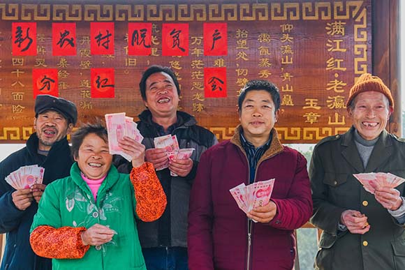 綦江区石角镇新农村村委会广场，村民展示自己的领到的分红款。陈星宇 摄