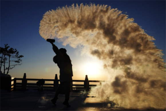 1月14日，在抚远市东极阁，游客在日出时玩“泼水成烟”。新华社记者 王建威 摄