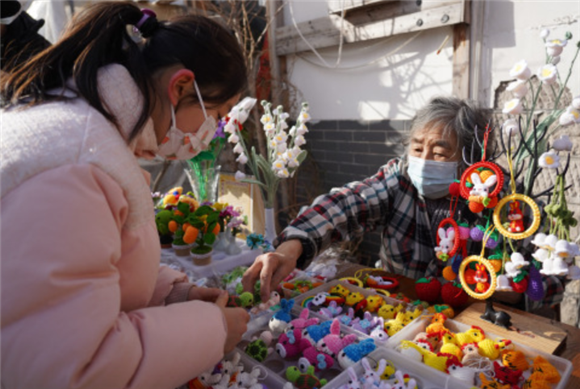 1月18日，一名儿童在济南曲水亭历史文化街道挑选手工艺品。新华社记者 朱峥 摄