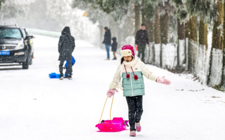 山王坪景区外，小朋友拉着雪橇玩具奔跑在雪地里。 胡波 摄