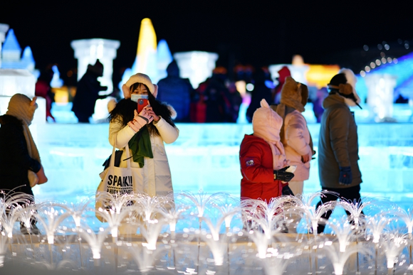 游客在哈尔滨冰雪大世界园区内游玩、拍照。