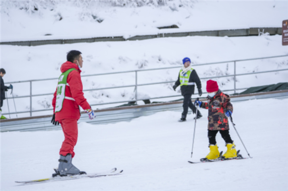 1月1日，在重庆市南川区金佛山景区滑雪场，一名小朋友在雪场教练的指导下练习滑雪。新华社记者 刘潺 摄