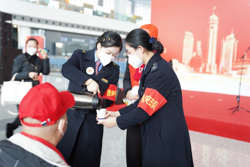 重庆西站工作人员为外出务工人员送上热水。