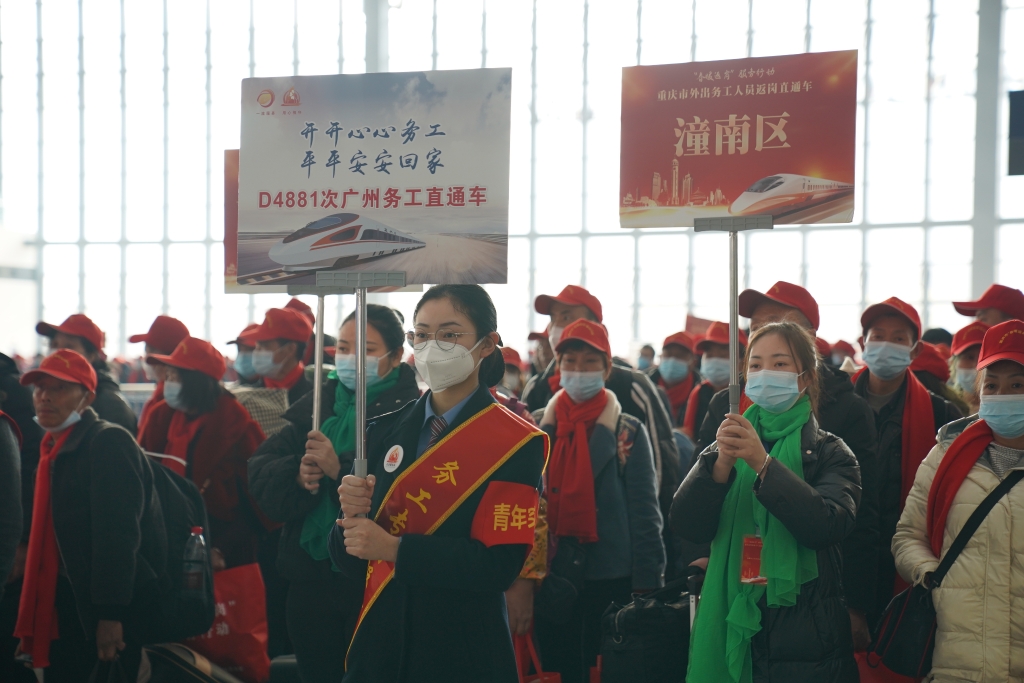 重庆西站工作人员举牌引导外出务工人员有序上车。