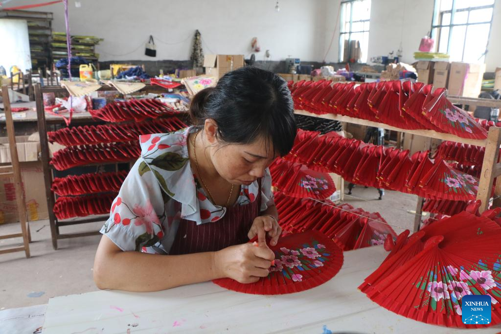 Yu Xiuying paints a wooden fan at the workshop of the Jiangxi Shenglian Fan Development Company Limited in Ganzhu Township in Guangchang County, east China's Jiangxi Province, on Sept. 12, 2023. (Xinhua/Zhu Yunuo)