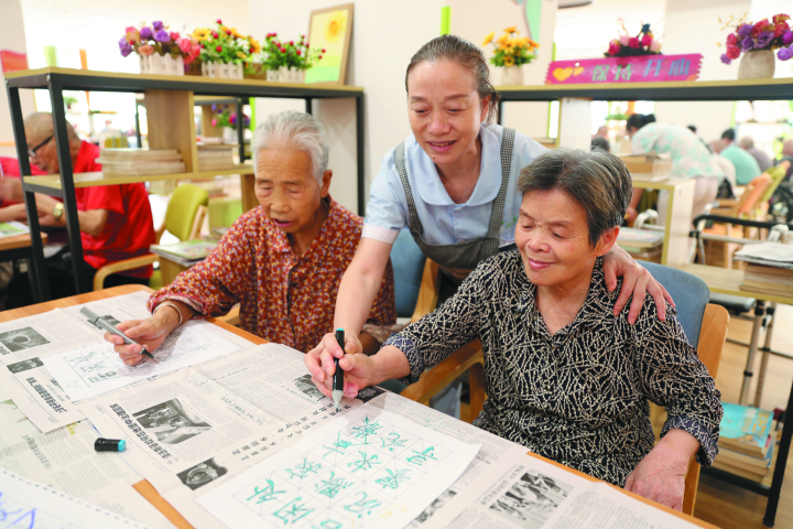 社区养老服务中心工作人员教老年人练字。资料图