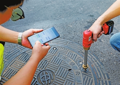 市政工作人员用手机给电动钥匙发送手机钥匙信号，用来打开智能井盖。 记者 刘陶然 摄