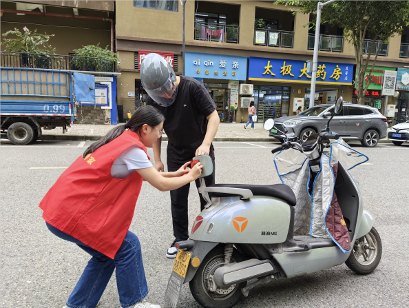 社区工作人员向骑两轮电动车的居民张贴反光标识。学智社区供图 华龙网发