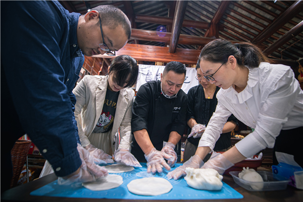 在慈城古县城景区内，年糕食品店主包珅（左三）带领游客体验年糕饺的制作。新华社记者 江汉 摄