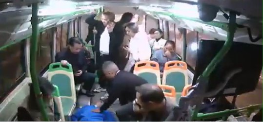 男子抽搐倒地，车上其他乘客帮忙掐人中。视频截图