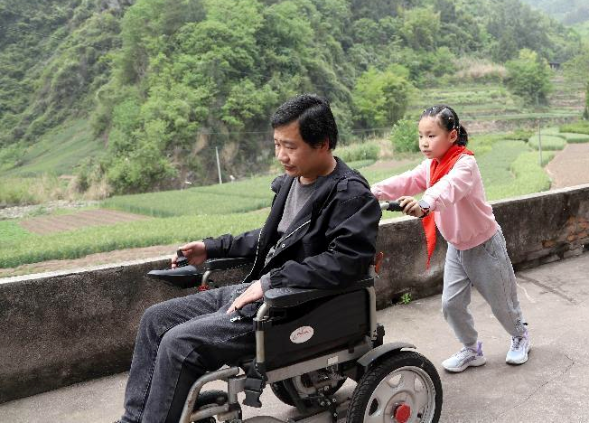 傅鑫怡为父亲推轮椅。云阳县委宣传部供图2