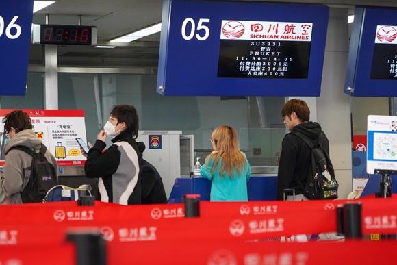 在成都双流国际机场T1航站楼，出境旅客在办理登机手续。