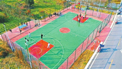 梁平区礼让镇川西村的全民健身路径，农家孩子在一块菜地旁的篮球场打篮球。记者 刘辉 摄