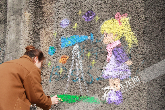 大学生志愿者为道路旁的围墙涂鸦。华龙网-新重庆客户端 张颖绿荞 摄