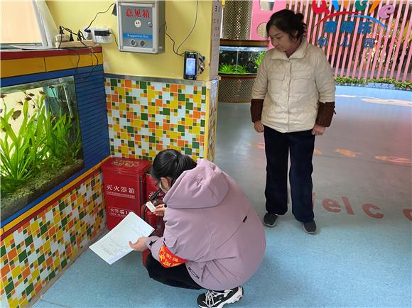 2社区安全员对幼儿园内消防器材的详细信息进行核准。通讯员 丘利成 摄