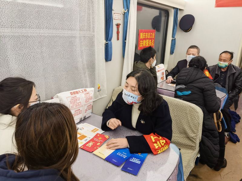 普快列车上的重庆市总工会法律服务点，不少返程务工人员前来咨询。市总工会供图