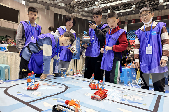 “冰雪运动会”现场，选手们围观机器人表演。华龙网-新重庆客户端 张颖绿荞 摄