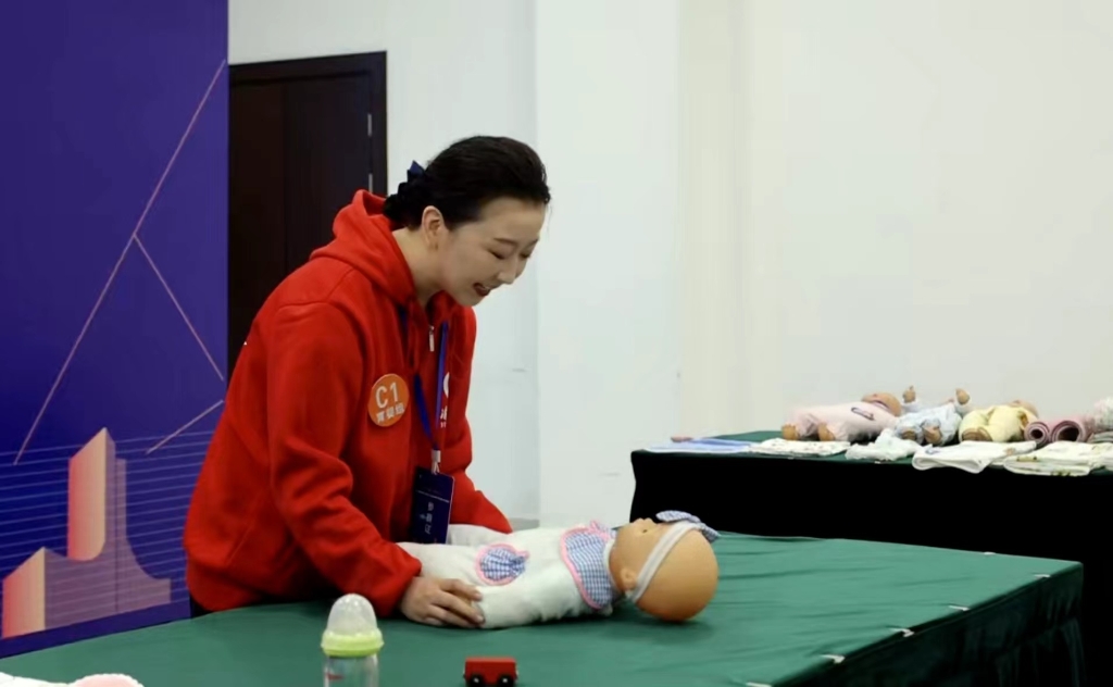 参赛选手正在用婴儿模特比拼抚触手法。重庆市人力社保局 供图