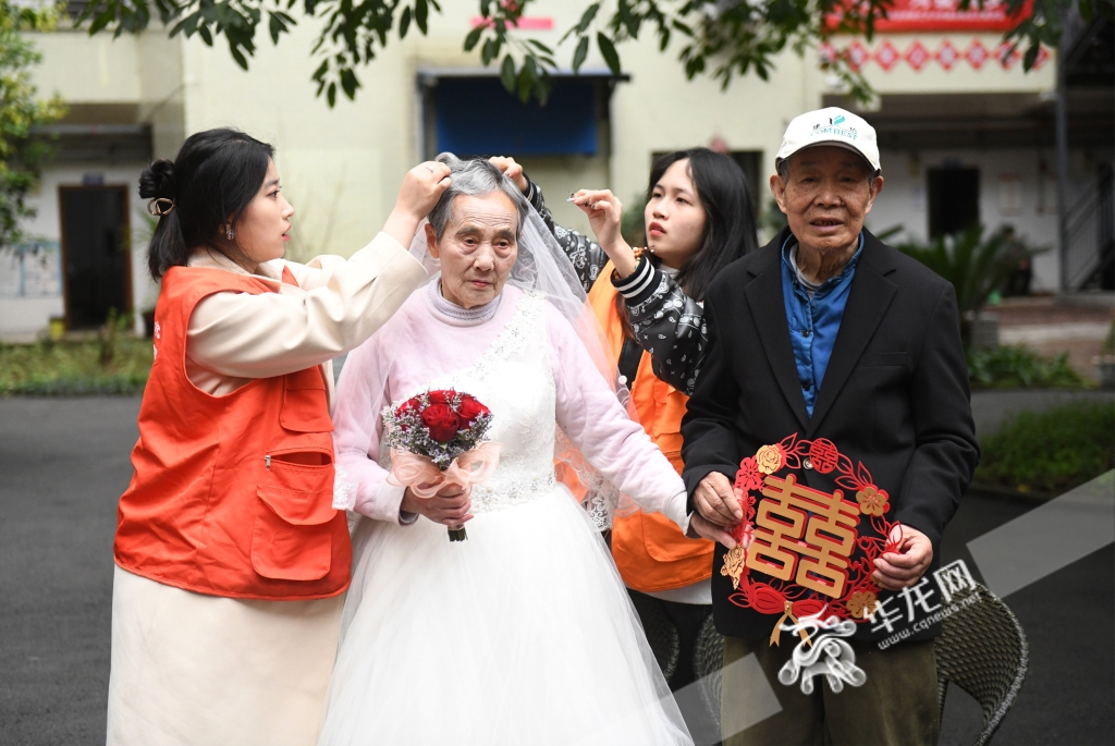 志愿者正在为老人整理婚纱。华龙网-新重庆客户端记者 秦思思 摄 