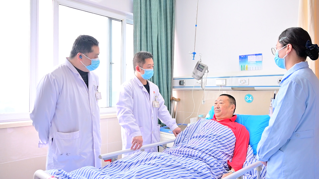 但汉彬（左二）查房了解患者恢复情况 摄影/王裕庆