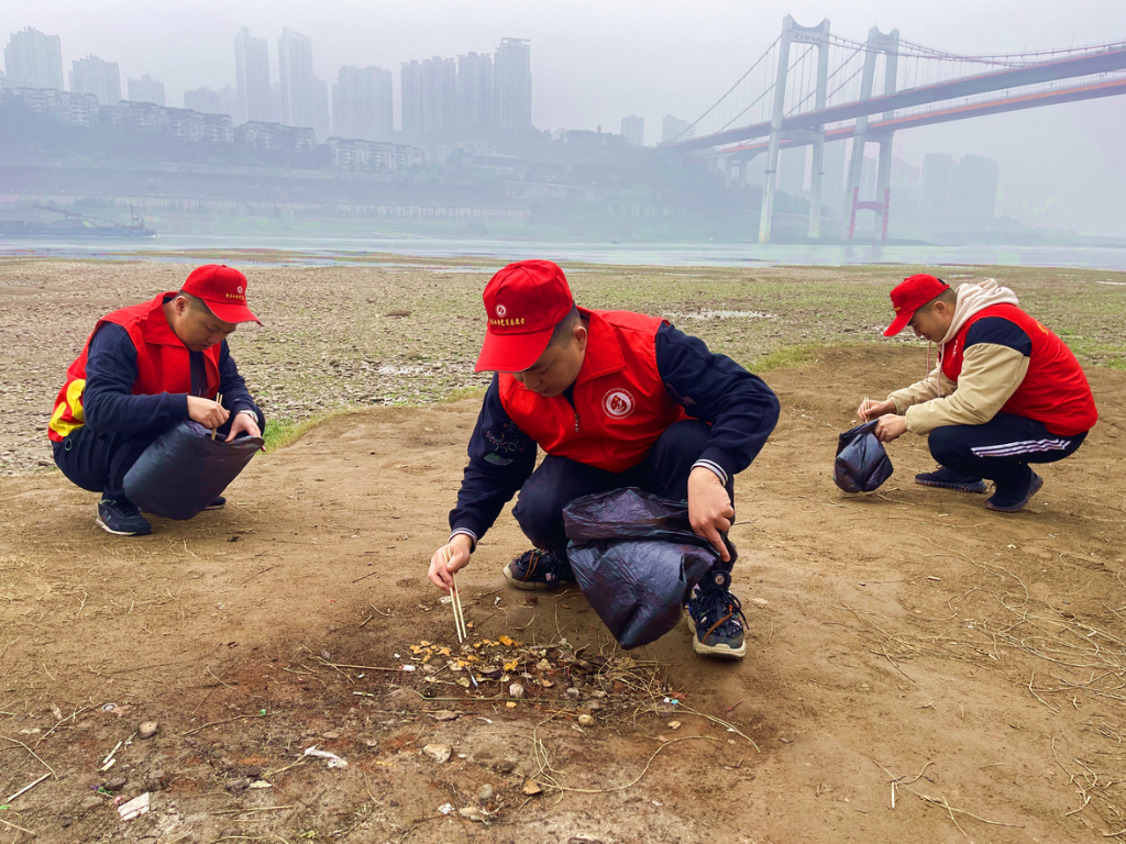市自来水公司九龙分公司党员志愿者在江岸边，认真清理烟头、塑料品等垃圾。重庆水务集团供图