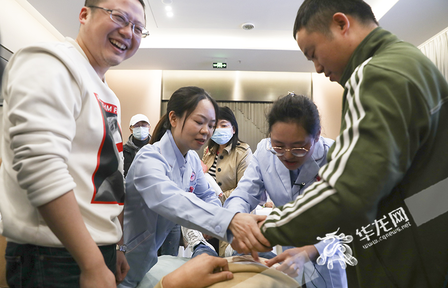 01 新手爸爸们在医护人员的指导下,学习如何为产妇绑腹带。