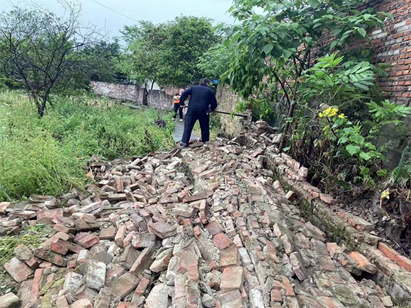 1巡查队员冒雨清理垮塌围墙。通讯员 刘梅 摄