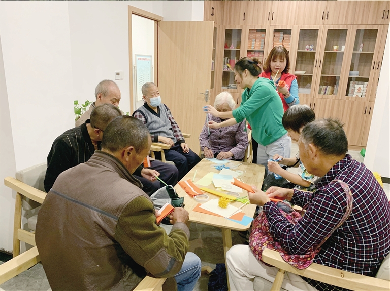 回兴街道高岩路社区养老服务站工作人员耐心指导残疾老年人做手工。记者 杨青 摄