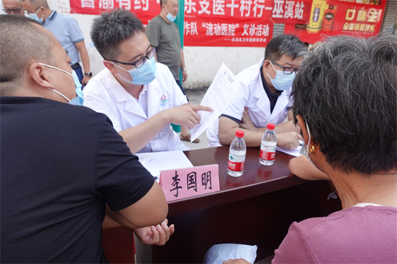 参加义诊的医生正在给居民看病历。巫溪县乡村振兴局供图 华龙网发