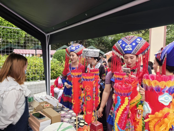 壮乡美女在市级非遗代表性名录——龙凤花烛展位前憧憬自己美好的未来